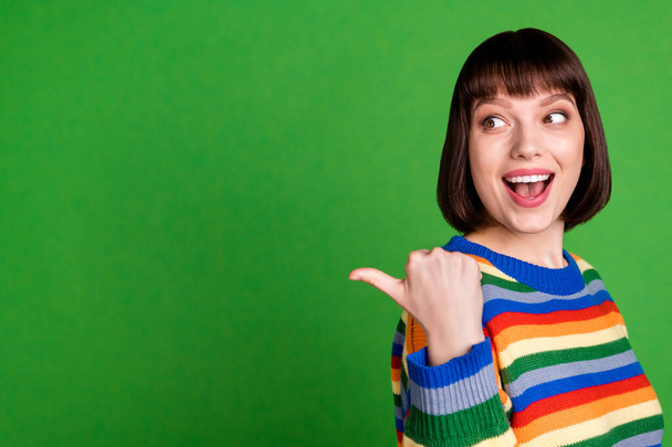 Photo of excited happy young woman look point finger empty space sale news smile isolated on green color background - Zdjęcie, obraz