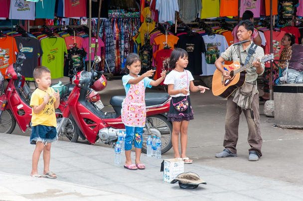  Kanchanaburi, thailand - 23 mei 2014: niet-geïdentificeerde kinderen zingen en volwassene gitaar te spelen op de straat te verkrijgen geld op 23 mei 2014 in kanchanaburi, thailand - Foto, afbeelding