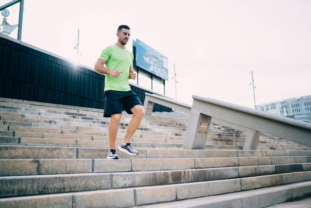 Svalnatý muž běžec v teplákové soupravě těší aktivní životní styl na kardio cvičení pocit vitality a wellness, silný muž jogger trénink vytrvalost a svalovou sílu na stadionu městských prostředí - Fotografie, Obrázek