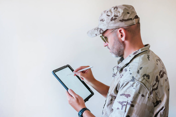 Homem caucasiano com uniforme de exército camuflado usando um tablet, conceito de tecnologia. - Foto, Imagem