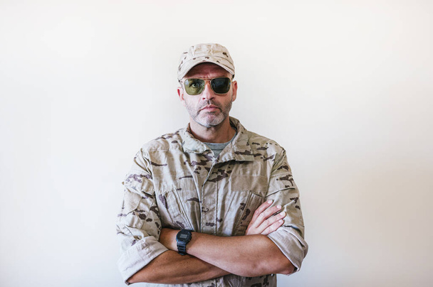 Uomo caucasico in uniforme militare camuffata che attraversa le braccia - Foto, immagini