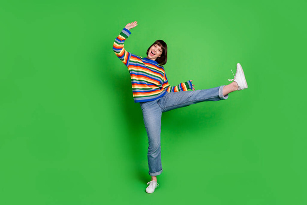 Foto de longitud completa de bastante encantadora dama joven vestido colorido pulóver bailando sonriente aislado color verde fondo - Foto, Imagen