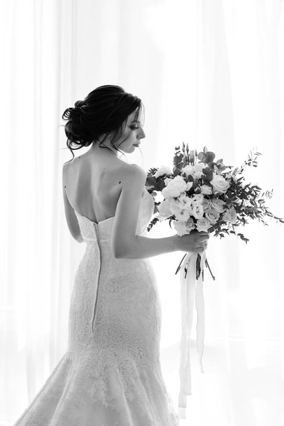 νύφη σε λευκό φόρεμα με μπουκέτο σε δωμάτιο ξενοδοχείου - Φωτογραφία, εικόνα