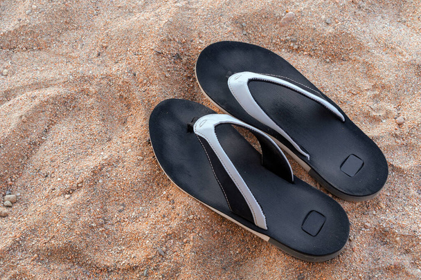 Mens beach shoes on the sand. Black flip-flops - Foto, afbeelding