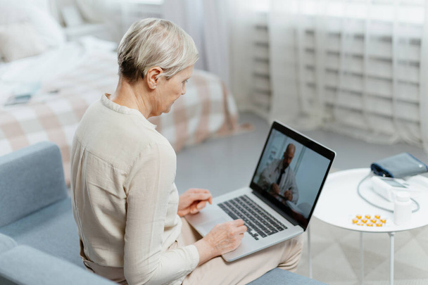 señora madura usando el ordenador portátil para la consulta de vídeo con su médico. - Foto, Imagen