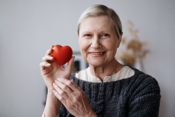 smiling mature woman with a red heart in her hands . - Valokuva, kuva