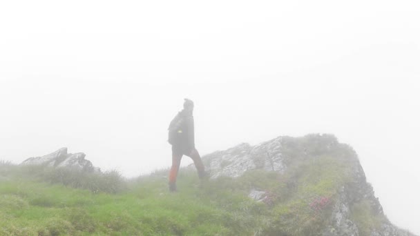 Dağdaki kayalıklarda sis ile yürüyen bir yürüyüşçüyle göz kamaştırıcı bir manzara. - Video, Çekim