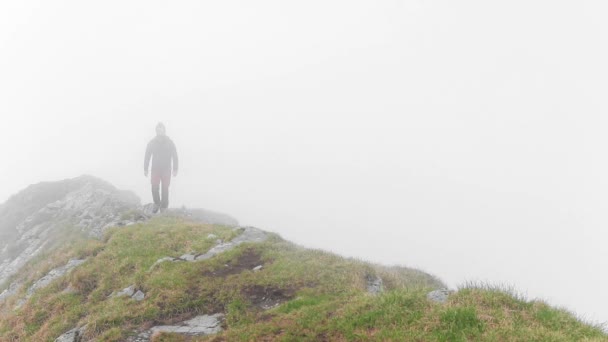 Dağdaki kayalıklarda sis ile yürüyen bir yürüyüşçüyle göz kamaştırıcı bir manzara. - Video, Çekim