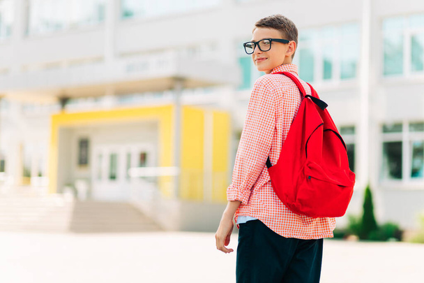 Portrait of a serious schoolboy boy in glasses with a backpack, Happy boy with a backpack and books goes to school, The beginning of a new school year after summer holidays - Foto, Imagen