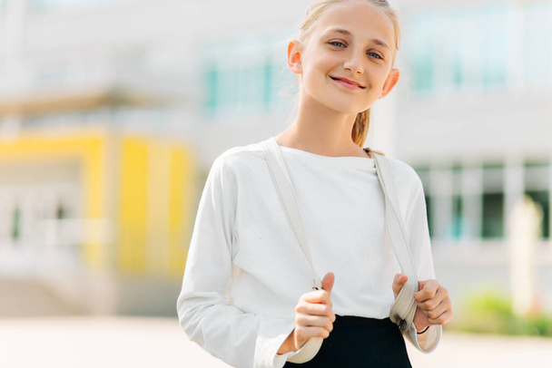 Primary school student, Happy girl with a backpack near the building outdoors, Start of lessons, The first day of autumn. - Fotoğraf, Görsel
