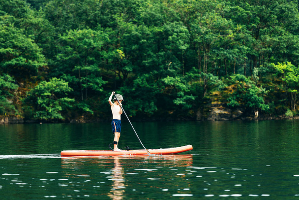 Feliz niño activo en el tablero de paddle en el agua - Foto, imagen