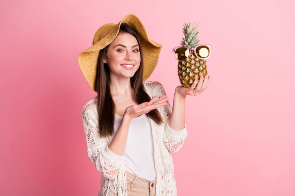 Muotokuva positiivinen kaunis tyttö aseita suoraan esittää ananas aurinkolasilla eristetty vaaleanpunainen väri tausta - Valokuva, kuva
