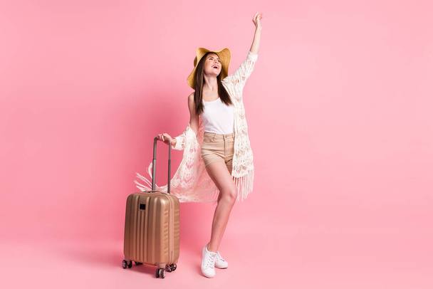 Photo of pretty shiny young lady wear lace cardigan cap smiling holding bag rising arm empty space isolated pink color background - Photo, Image