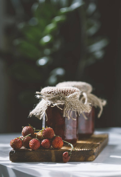 Strawberry jam with fresh strawberries on a wooden board - Fotó, kép
