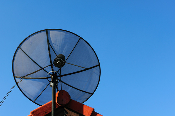Спутниковая тарелка на крыше на голубом фоне неба утром
. - Фото, изображение