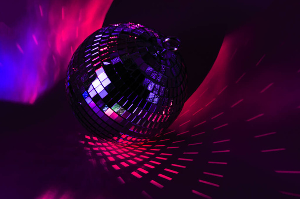 Disco ball shining in red light. party ball Laying in the dark - Photo, Image