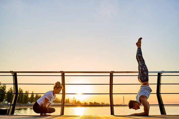 Couple doing practicing yoga together on nature outdoors . Morning exercises at the sunrise. - Photo, Image