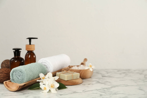 Composition with beautiful jasmine flowers and skin care products on white marble table, space for text - Valokuva, kuva