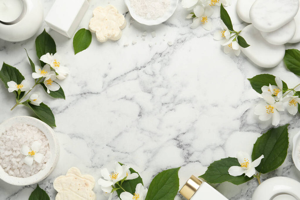 Jasmínové květiny a sada lázeňských potřeb na bílém mramorovém stole, plochý ležel. Mezera pro text - Fotografie, Obrázek