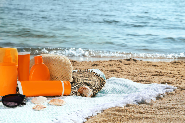Sun protection products and beach accessories on blanket near sea, space for text - Фото, зображення