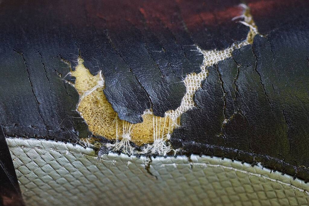 parte de la tapicería vieja hecha de cuero desgarrado gris negro con un agujero - Foto, imagen