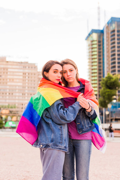 Donna lesbica giovane coppia multietnica con una bandiera arcobaleno. Concetto di diversità - Foto, immagini