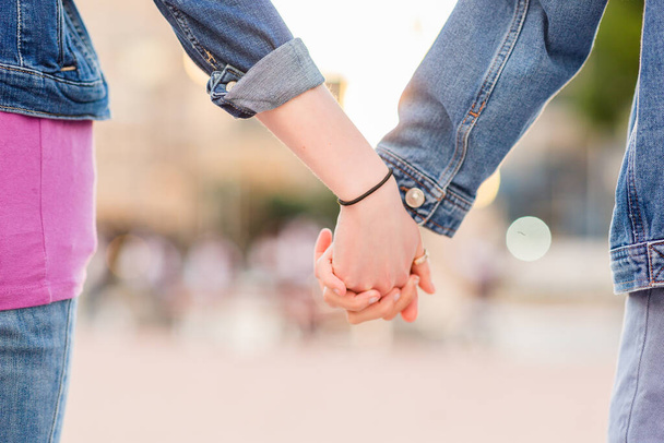 Unrecognizable lesbian couple holding hands. Young dating together in a female relationship - Photo, Image