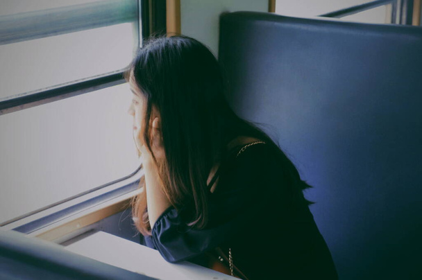 νεαρή γυναίκα που κάθεται στο παράθυρο και κοιτάζει την κάμερα - Φωτογραφία, εικόνα