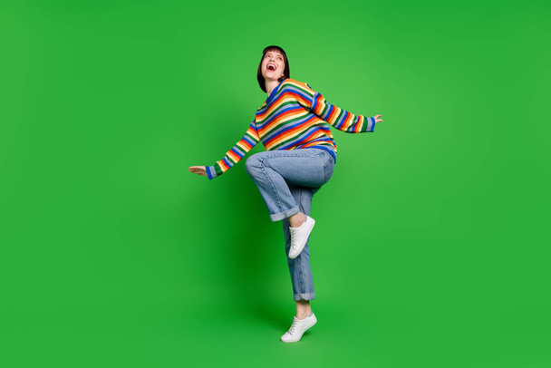 Full length photo sweet charming excited young lady dressed colorful pullover dancing smiling isolated green color background - Valokuva, kuva