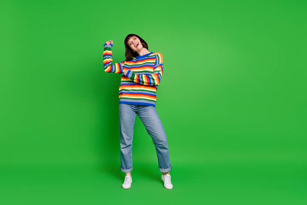 Full length photo of cute funky young woman wear striped sweater smiling dancing isolated green color background - Foto, Bild