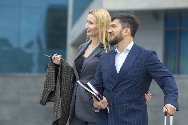 hommes d'affaires réussis partenaires homme et femme sur le fond d'un bâtiment d'entreprise avec des documents dans leurs mains discuter de projets d'entreprise - Photo, image