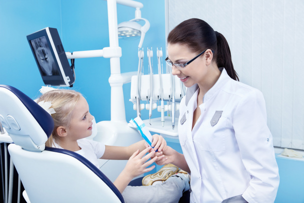 Стоматолог дает пациенту зубную щетку и зубную пасту
 - Фото, изображение