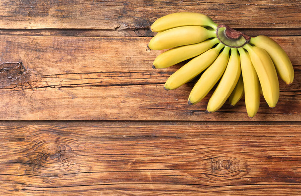 Bunch of ripe baby bananas on wooden table, top view. Space for text - Fotoğraf, Görsel