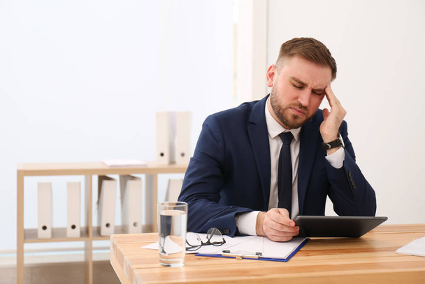 Man suffering from migraine at workplace in office - Photo, image