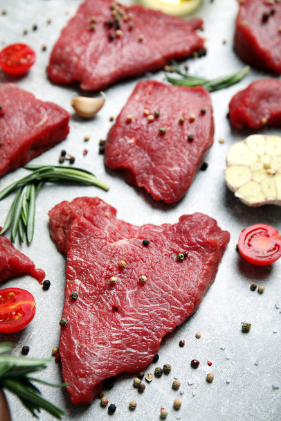 Fresh raw meat steaks and spices on light grey table - Zdjęcie, obraz