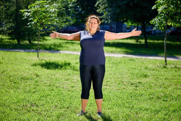 Obese European woman doing morning exercises in nature. - Φωτογραφία, εικόνα