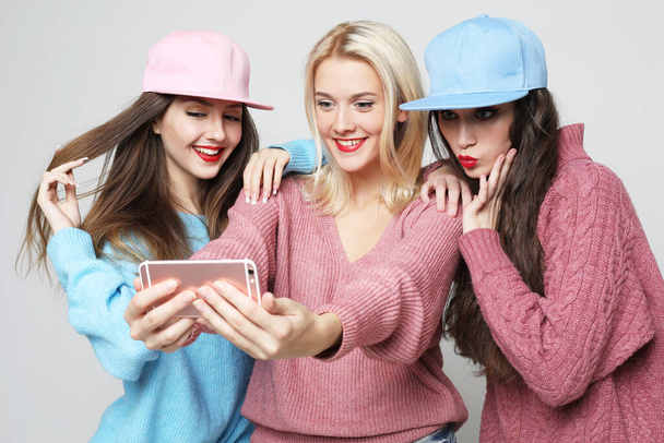 Three young smiling hipster women.Girls taking selfie self portrait photos on smartphone. Female showing positive face emotions. - Foto, immagini