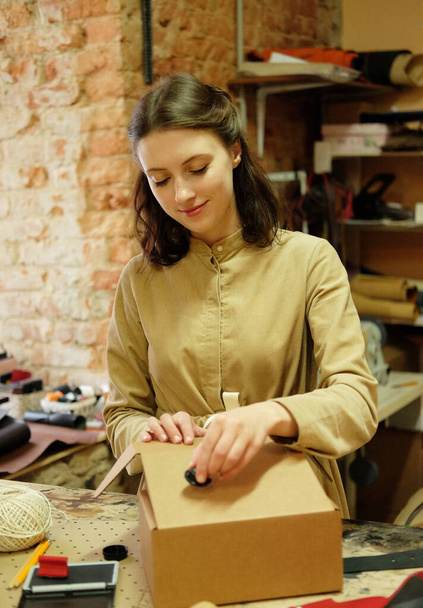 woman folds packing box in sewing workshop - Foto, Bild