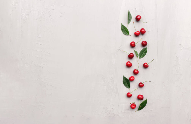 Плоский вид сверху на сером бетонном фоне, сладкие ягоды вишни, кубики льда - Фото, изображение