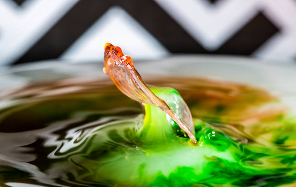 Een waterdruppel terugkaatst uit een plas water om een prachtig beeld te creëren - Foto, afbeelding