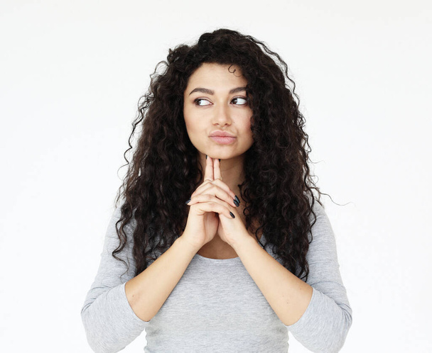 Attractive mixed race female actress wearing grey shirt, standing against white wall during audition - Photo, Image