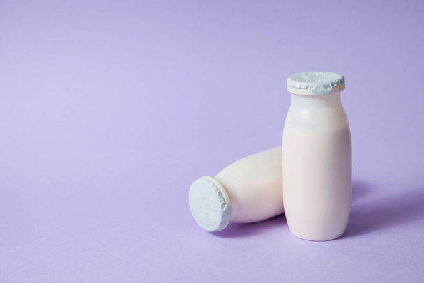 Bottles with probiotics and prebiotics dairy drink on light purple background. Bio yogurt with useful microorganisms. Production with biologically active additives. Fermentation and diet healthy food. - Foto, Imagen