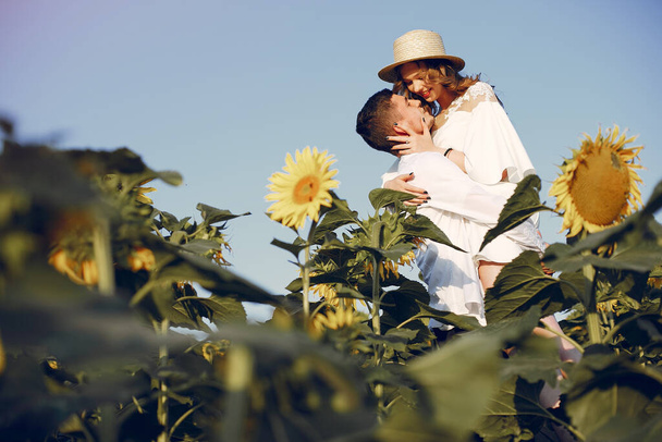 Beautiful and stylish couple in a field wirh sunflowers - Photo, Image