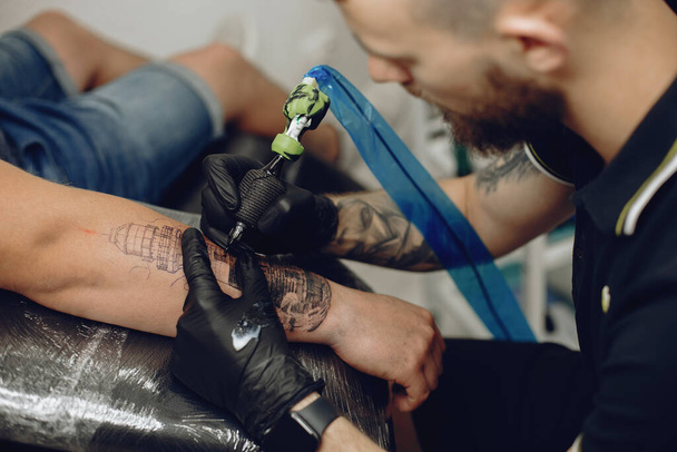 Man doing a tattoo in a tattoo salon - Fotó, kép