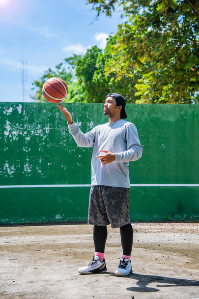Man exercising outdoors in the sun by playing basketball during the COVID-19 crisis, June 26, 2021, Surat Thani, Thailand. - Zdjęcie, obraz