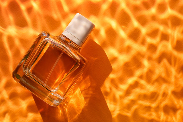 Bottle of perfume in water on color background, closeup - Photo, Image