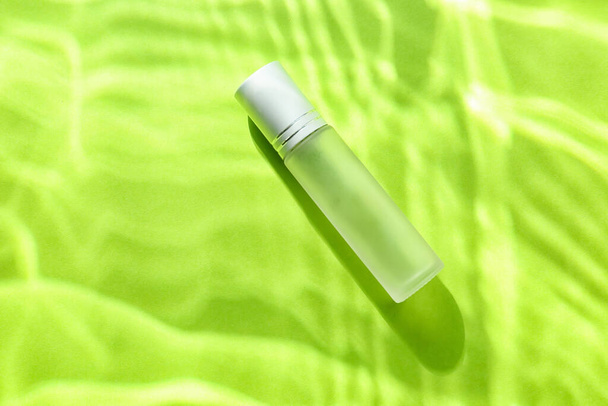 Egy üveg parfüm vízben, színes háttér - Fotó, kép