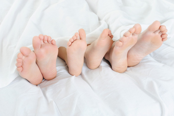 Close-up of the feet of a family on the bed. Isolated on white background - Valokuva, kuva