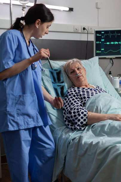 Sairaanhoitaja analysoi vanhempi potilas rintakehän röntgenkuva sairaalahuoneessa - Valokuva, kuva
