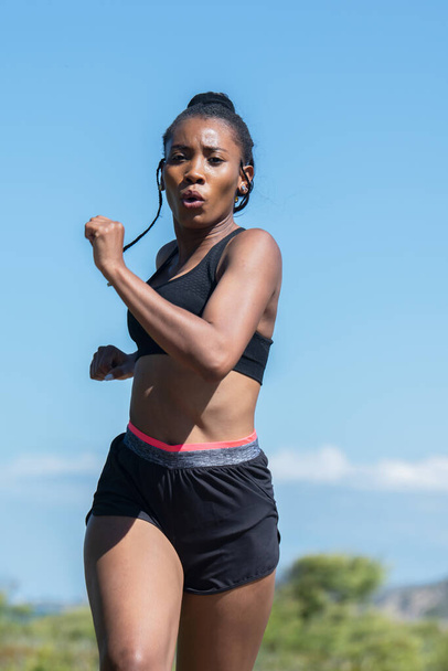 Афро-американка бегает на улице, глядя в камеру: концепция упражнений - Фото, изображение